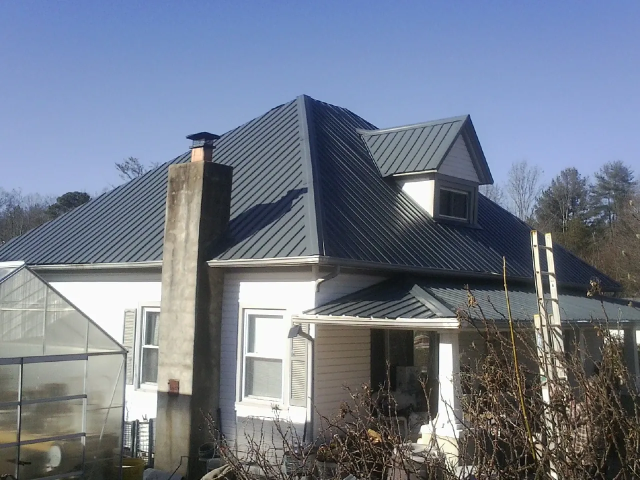 Dark blue standing seam metal roof on a white farmhouse with dormer — Slate & Tile Roof Repair by Roofing Brothers in Chester Gap