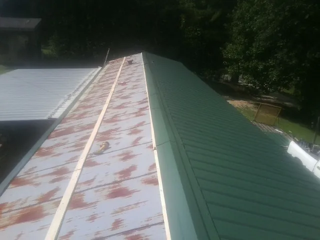 Old rusted panels beside newly installed green metal roofing — Wind Damage Roof Repair by Roofing Brothers in Chester Gap