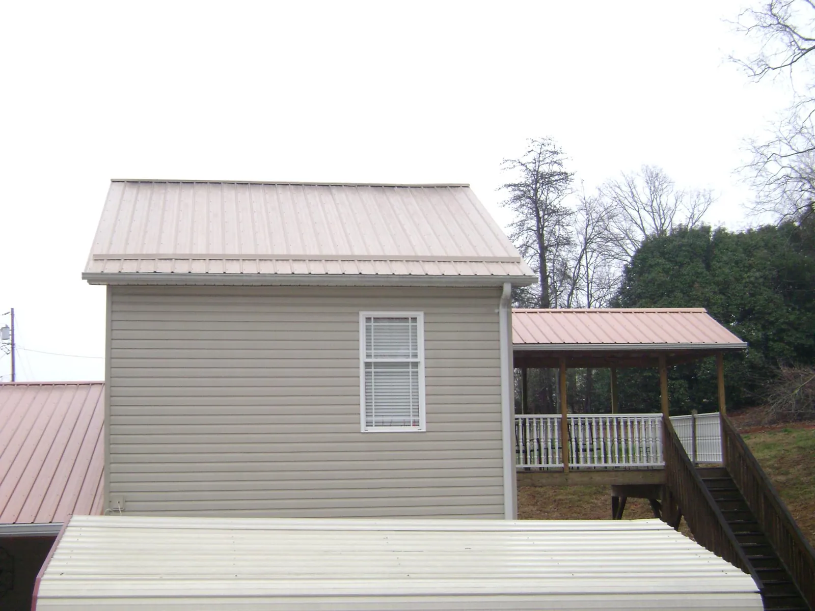 Tan metal roofs on a two story addition and attached porch, from a Roof Replacement job in Chester Gap
