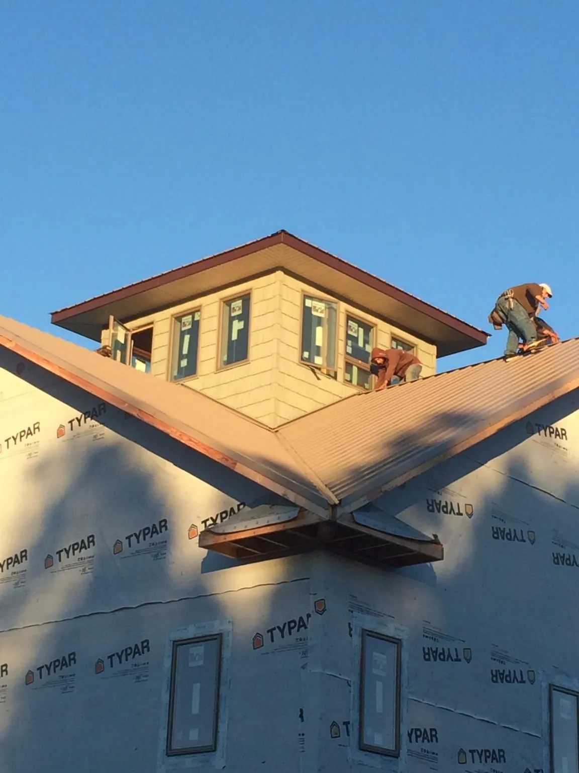 Roofers working around a rooftop cupola on a new metal roof at sunset — Roof Waterproofing in Chester Gap by Roofing Brothers